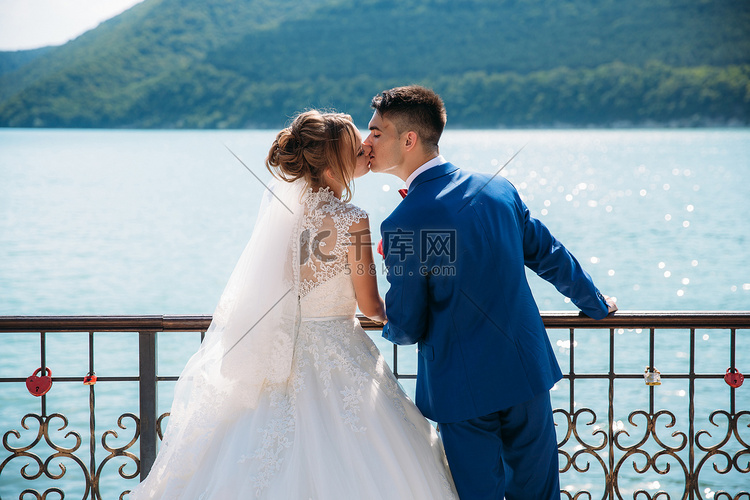 新婚夫妇在码头上温柔地亲吻着青