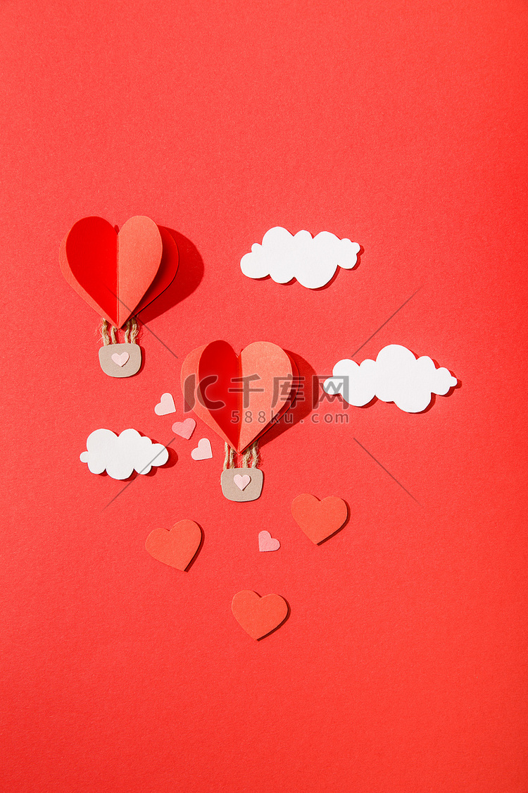 红色背景云彩中纸心形气球的顶部