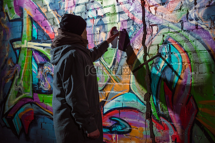 街头画家在晚上墙上涂上气溶胶颜