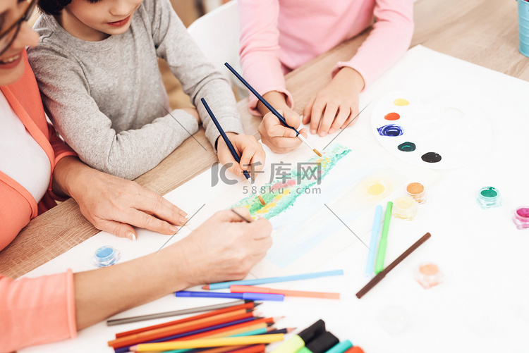 教儿童在家画画的老年妇女