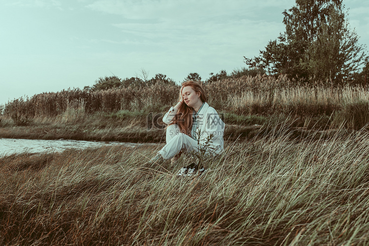 一位红润的年轻女子坐在湖边枯萎