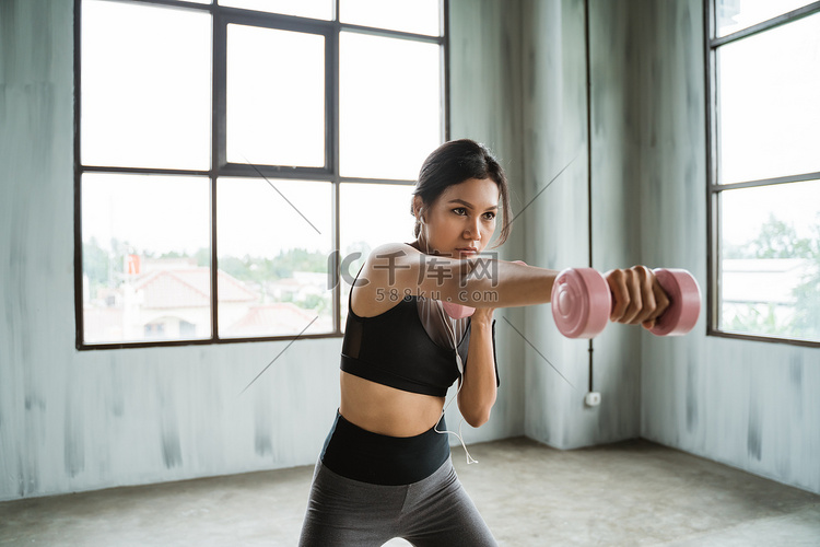 妇女拳打脚踢与哑铃在她的手