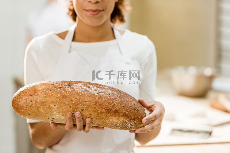 在烘焙生产中拿着新鲜面包的女贝