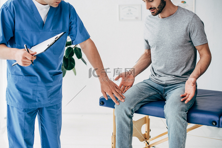 医生检查病人膝盖和在诊所按摩柜