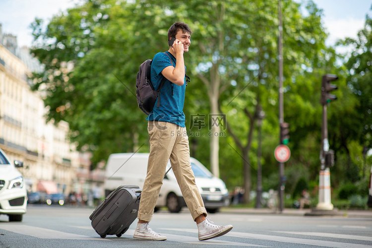 年轻游客拿着手机和手提箱在城市