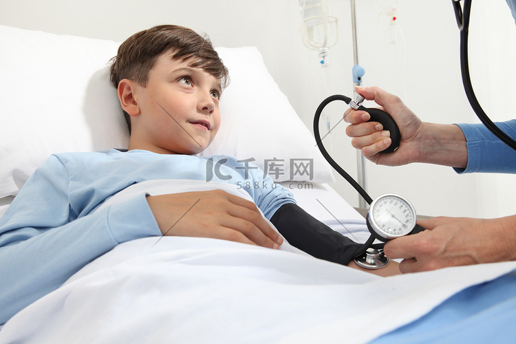 孩子躺在病房的床上，用血压计和