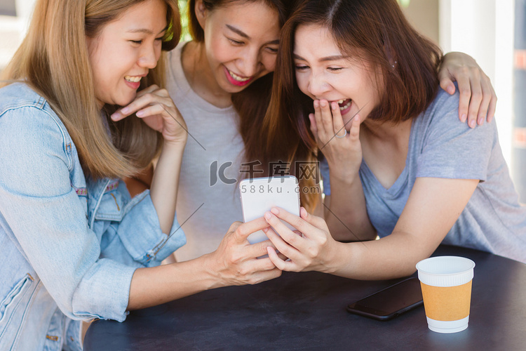 愉快的亚洲年轻妇女坐在咖啡馆喝