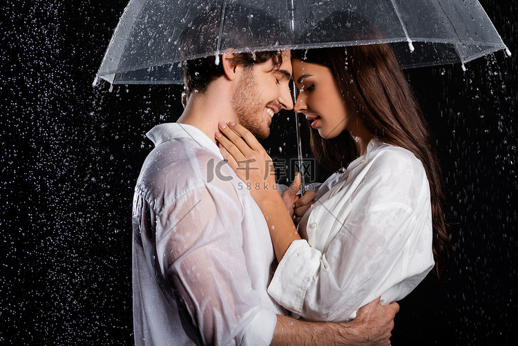 浪漫的年轻夫妇站在雨中，带着雨