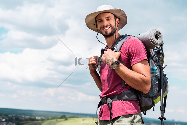微笑的旅行者在帽子与背包和旅游