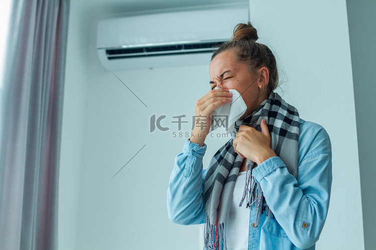 正在打喷嚏的妇女在家里的空调里