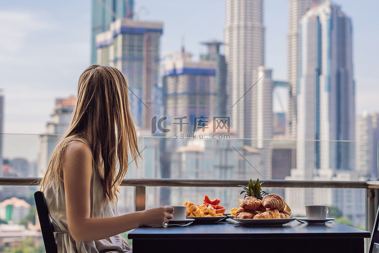 一个年轻的女人正在阳台上吃早饭