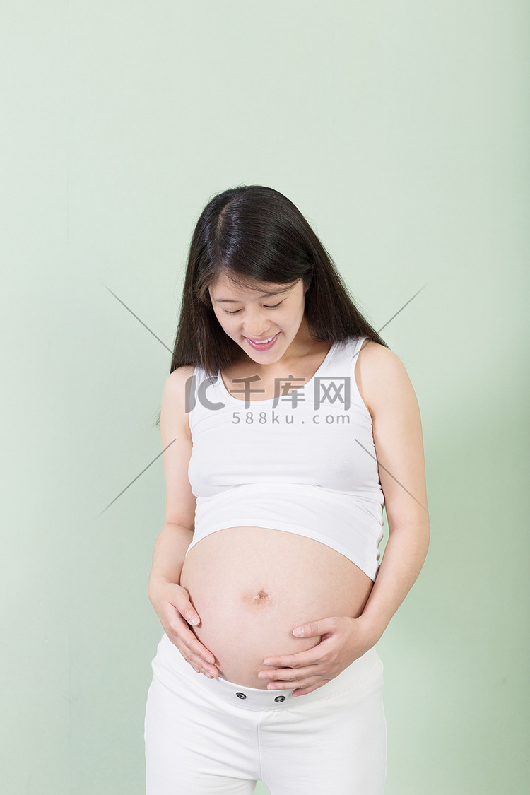 漂亮的孕妇肚子还盯着她的手的照