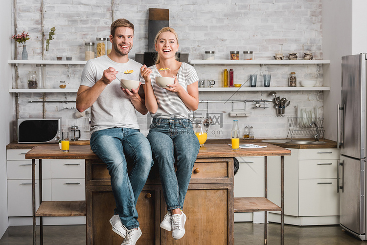 快乐夫妇吃早饭和坐在厨房柜台