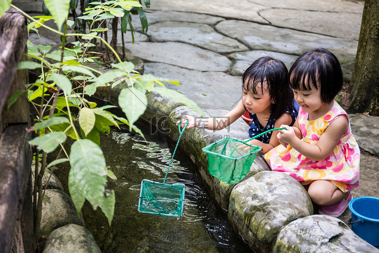 亚洲的中国小女孩用勺钓鱼网在池
