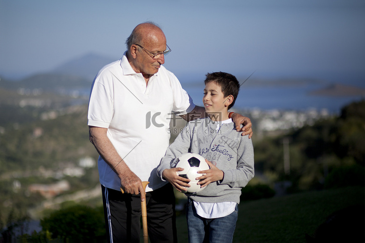 老人拿着一个足球球的小男孩