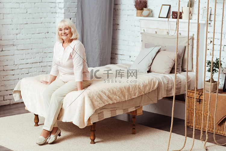 性格开朗的老年的妇女，坐在床上