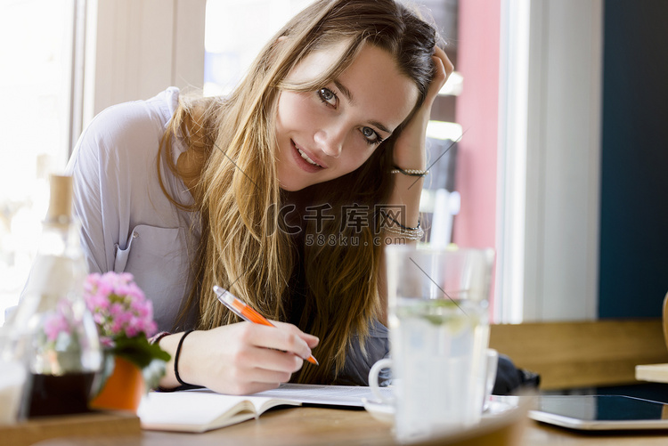 咖啡馆里的年轻女子在写作手放在