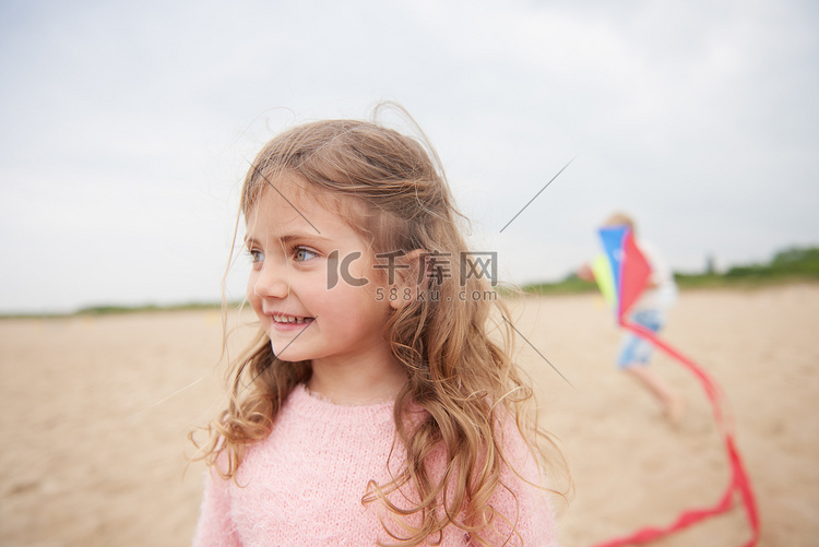 小女孩在海滩上微笑背景中有放风