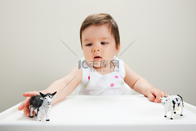坐在高脚椅上的男婴抱着玩具牛