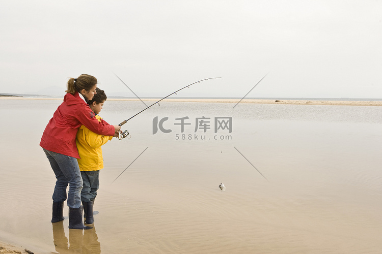 母亲在海滩教儿子钓鱼