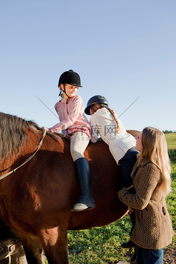 一名妇女帮助女孩骑马