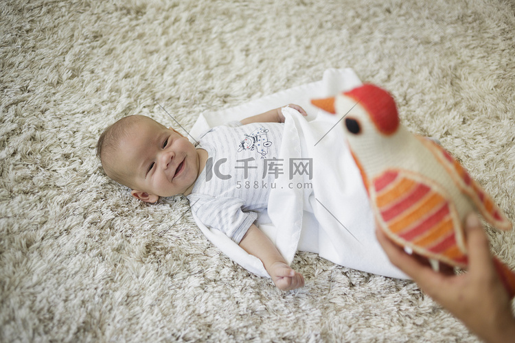 快乐的男婴看着玩具鸟