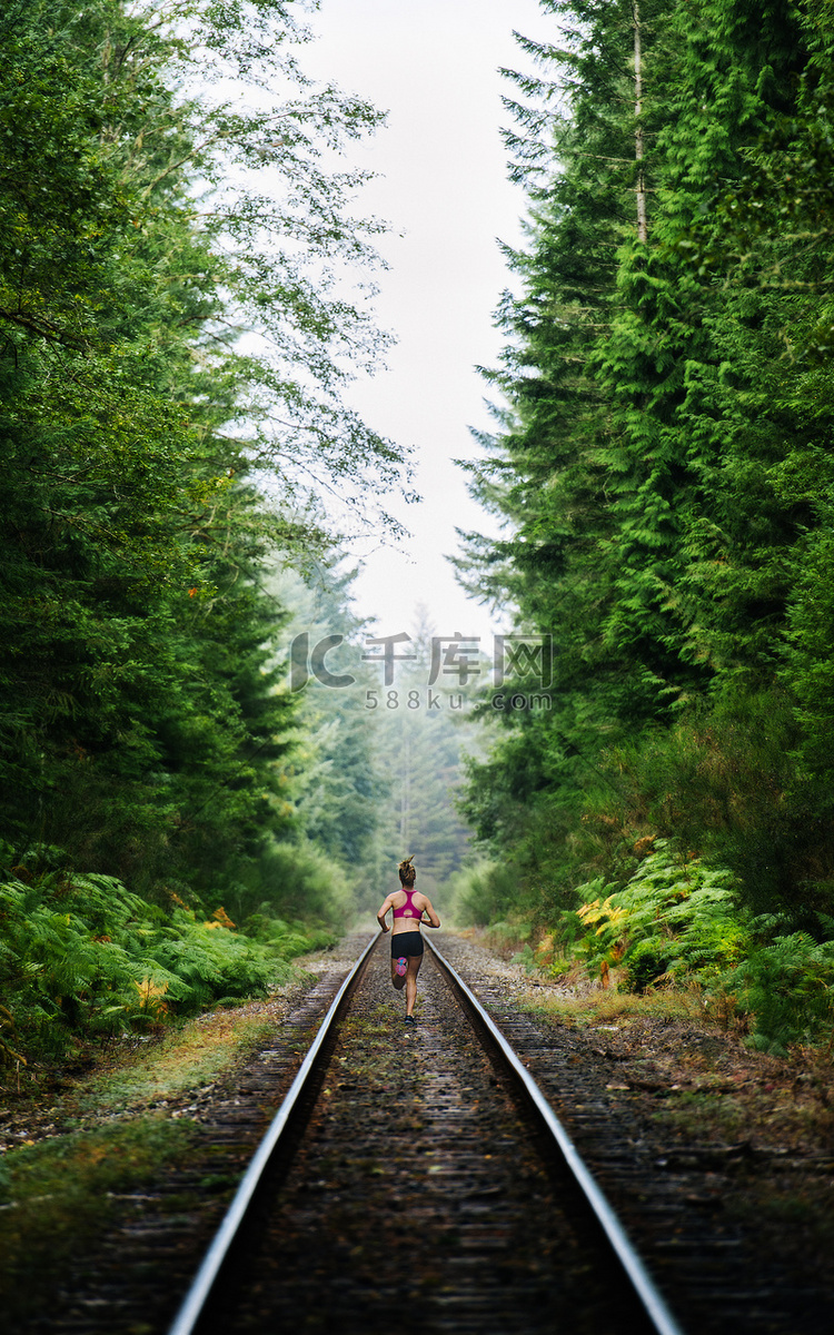 沿着乡村铁轨奔跑的年轻女子后视
