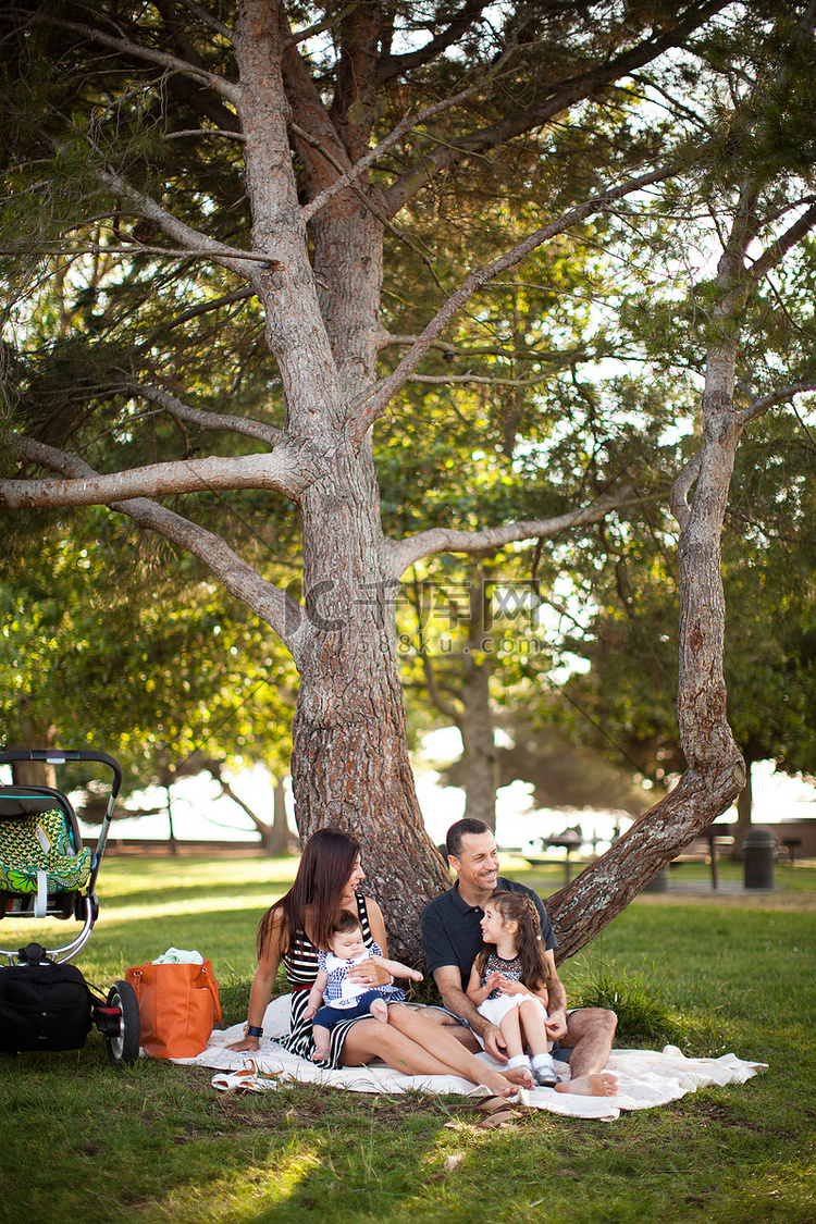 一家人和两个孩子坐在树下的野餐