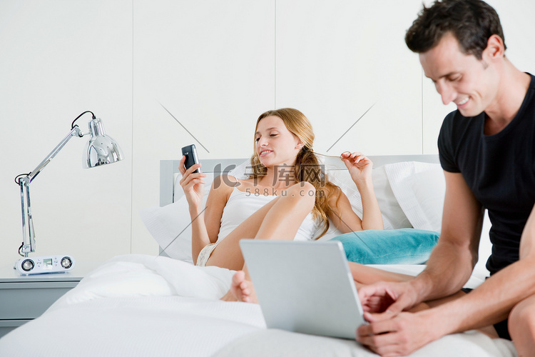 床上有笔记本电脑和掌上电脑的夫