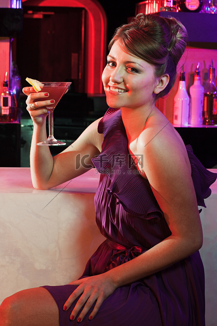 快乐的年轻女子坐在鸡尾酒吧里
