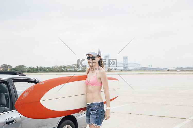 海滩上的中年妇女手持冲浪板