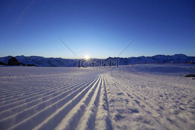 积雪覆盖的田野和群山上的日落奥