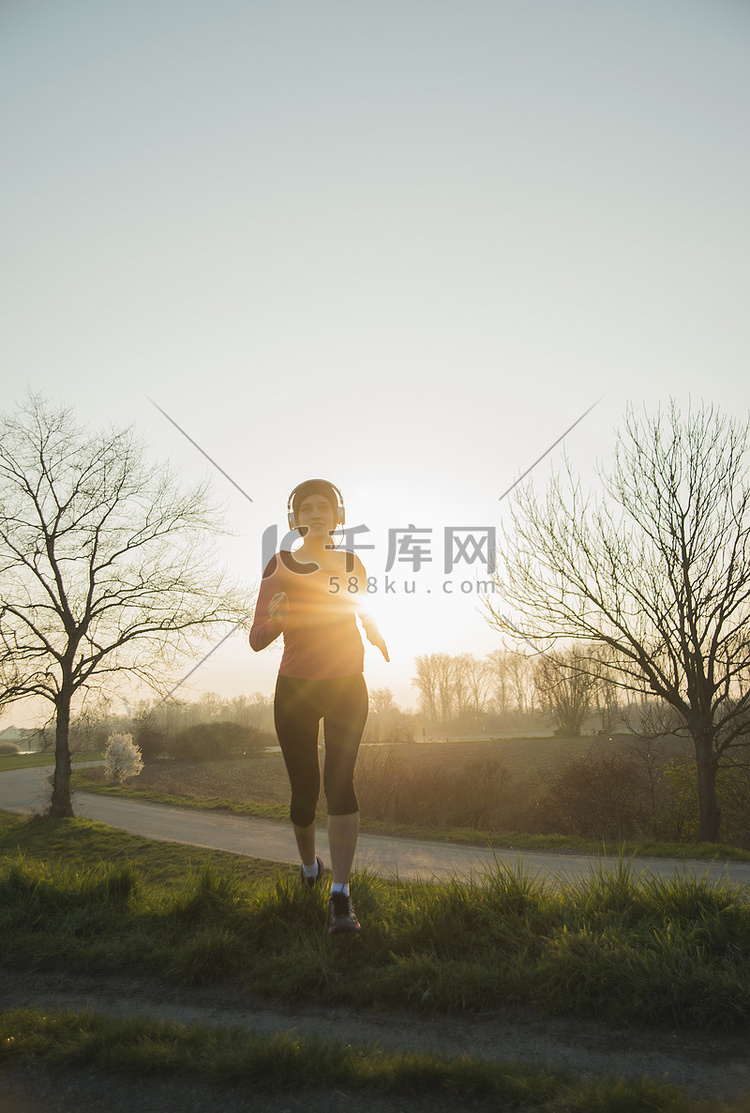 年轻的女跑步者在日落时跑步