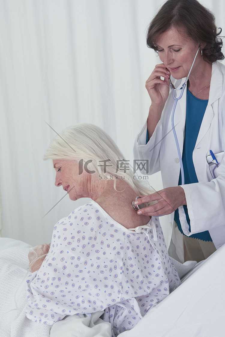女医生用听诊器听高龄女患者回诊