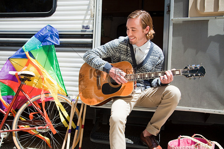 一名年轻男子在大篷车旁弹吉他