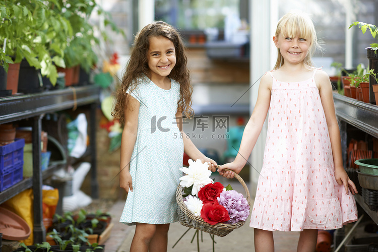 两个女孩在温室里提着一篮子鲜花