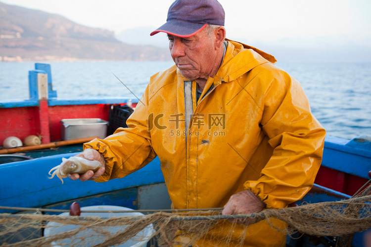 一名渔民在船上抓着鱿鱼