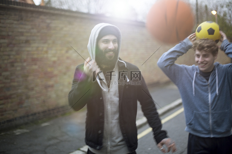 两个男人走在街上手里拿着足球