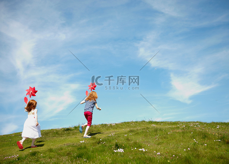 两个女孩带着风车在田野里奔跑