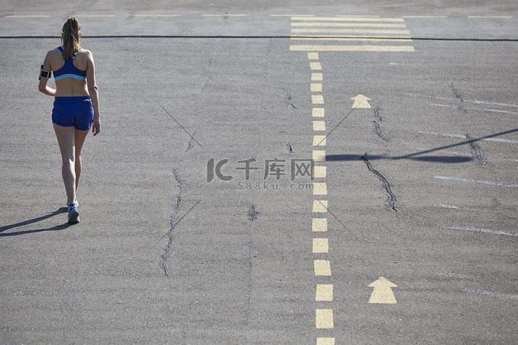 年轻女跑步者在停车场奔跑的后视
