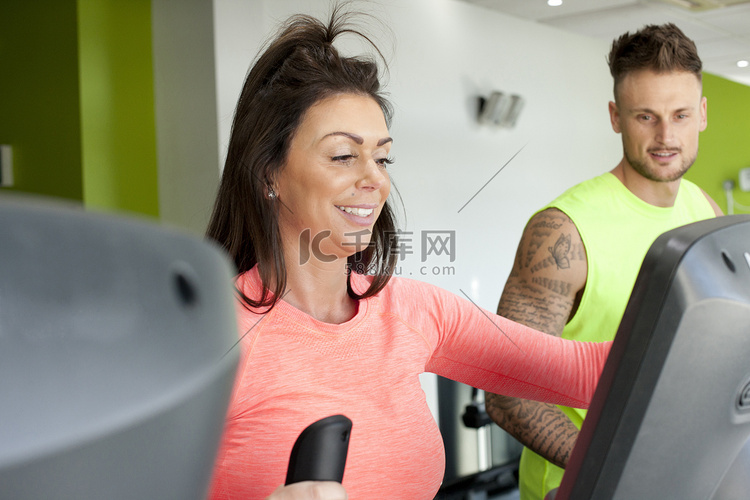 健身房里的男女在使用健身器微笑