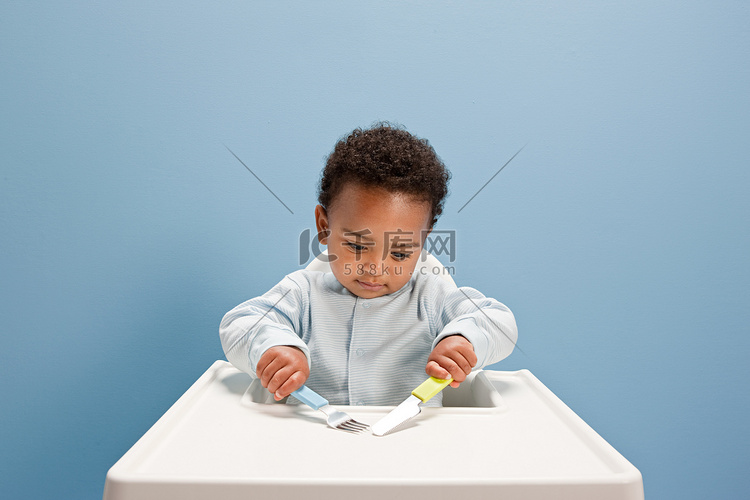 坐在高脚椅上的男婴用刀叉