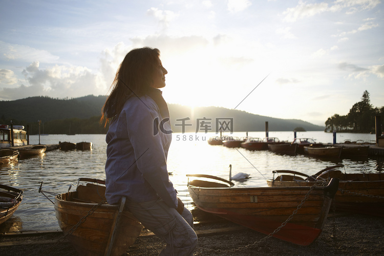 成熟的妇女坐在湖边的独木舟上英