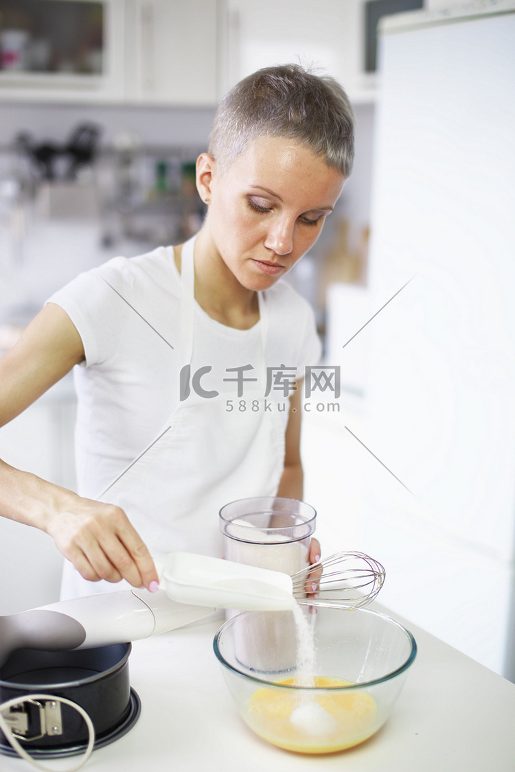 一名妇女将糖倒入搅拌碗中