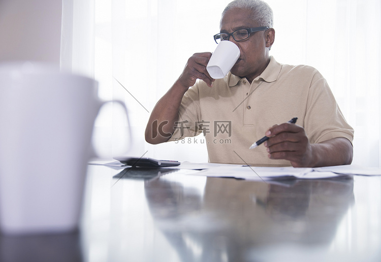一位年长的男子坐在桌子旁喝着热