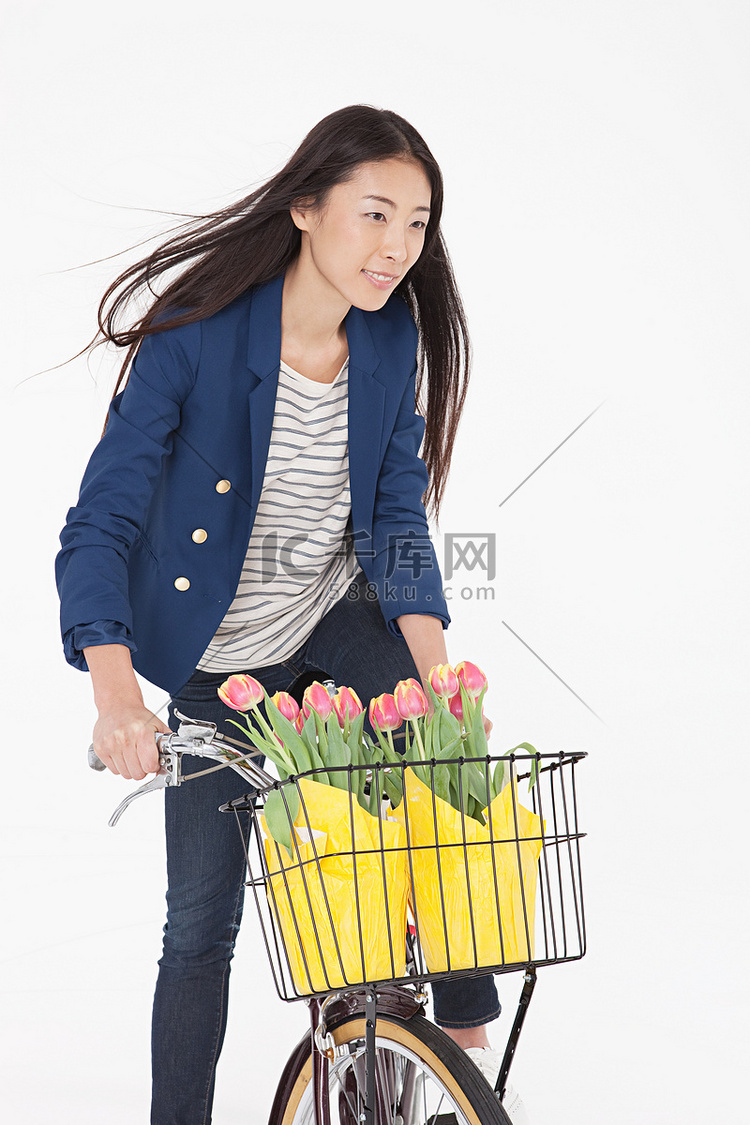一名女子骑自行车篮子里放着鲜花