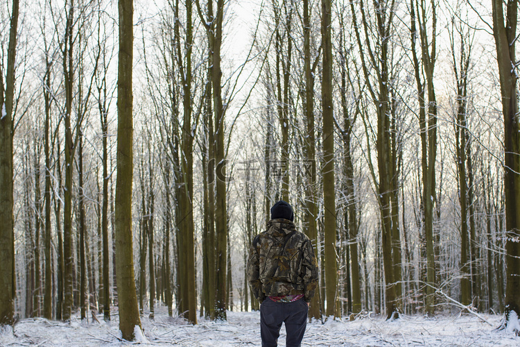 站在白雪覆盖的光秃秃的森林里的