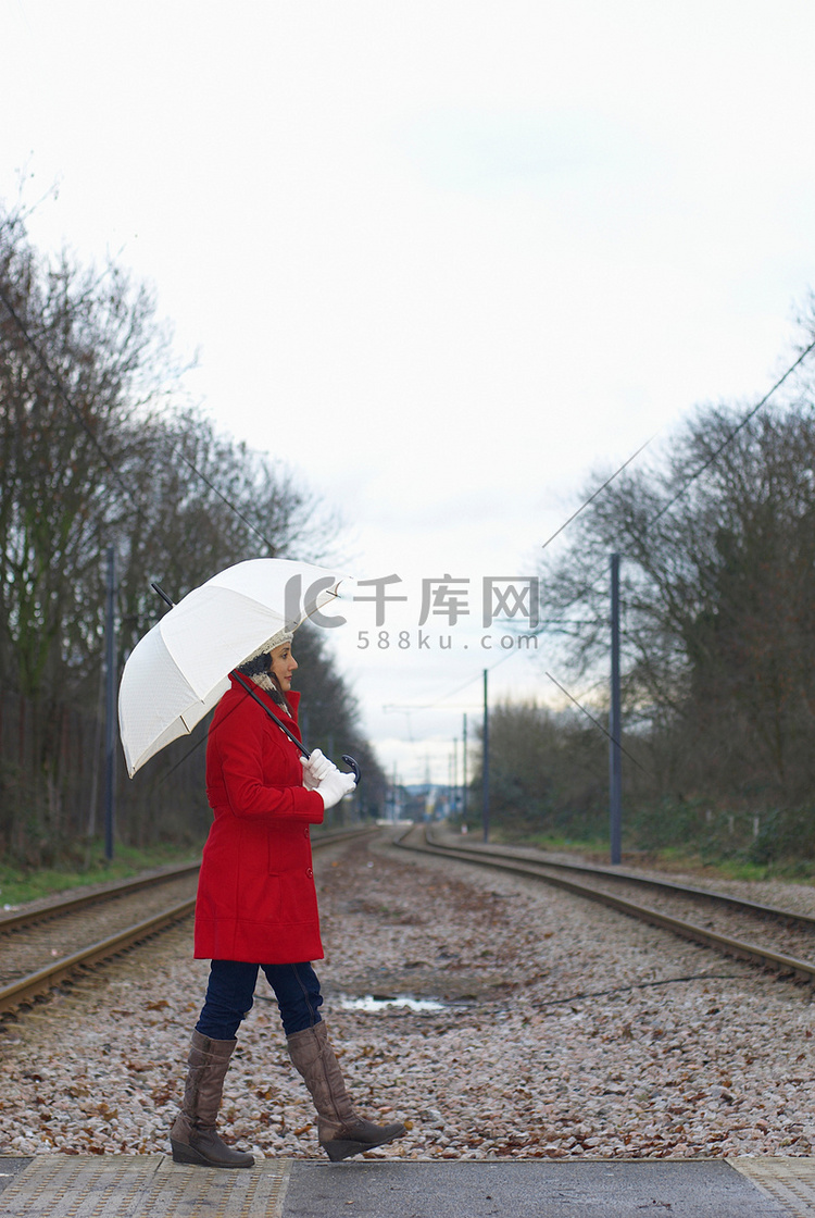 公园里穿红色夹克带雨伞的女孩