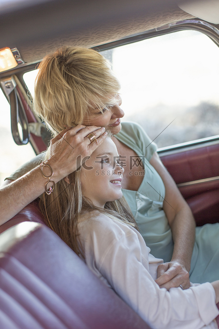 祖母和孙女坐在车的后座上面带微