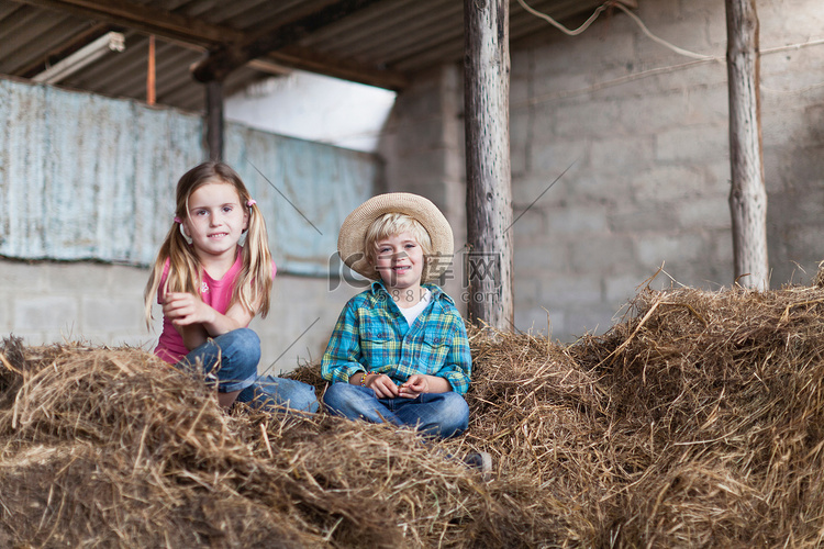 孩子们坐在马厩里的干草堆里